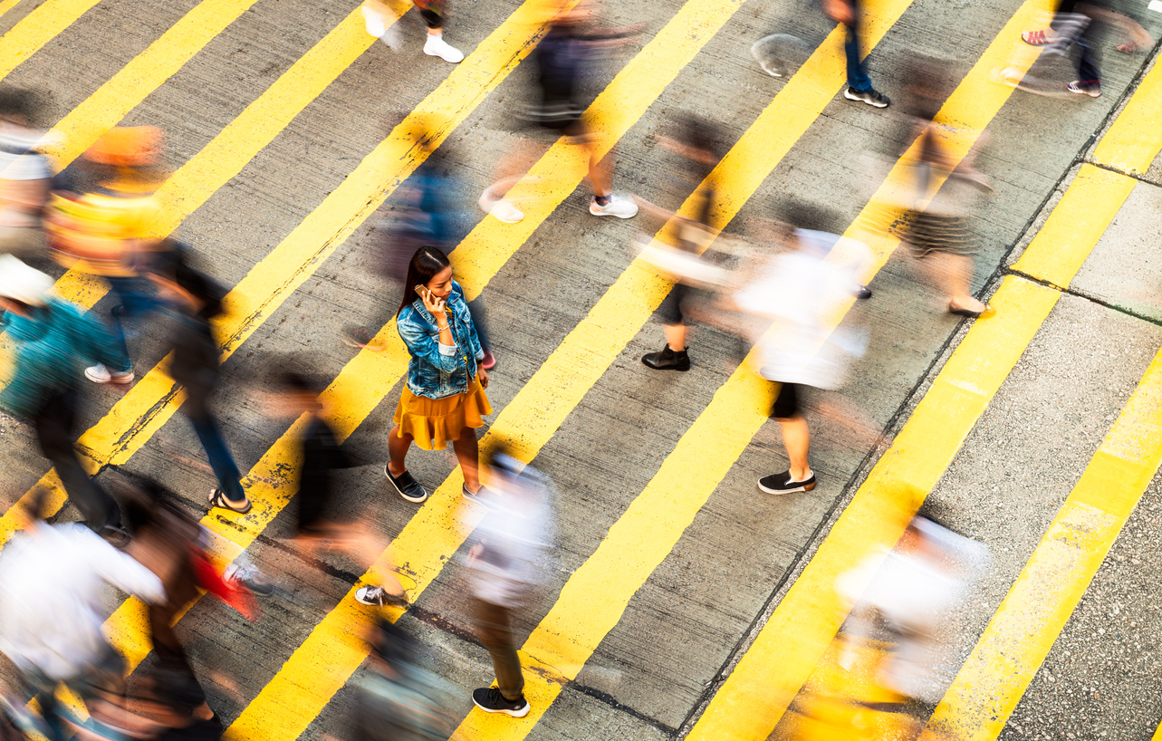 A person walking across a street with a group of people walking, illustrating Bi-Modal IT where organisations manage two distinct work styles, and Digital Transformation, reflecting the evolving landscape of business  and technology integration.